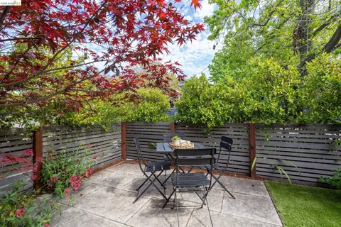 a backyard of a house with table and chairs and wooden fence