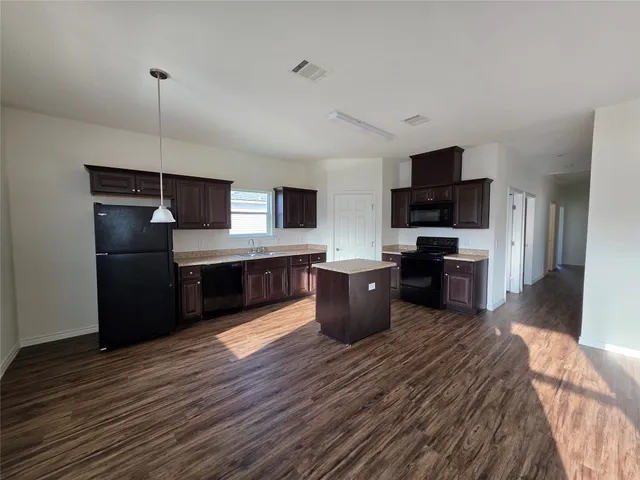 a kitchen with stainless steel appliances kitchen island granite countertop a stove top oven a sink dishwasher a refrigerator and a microwave oven