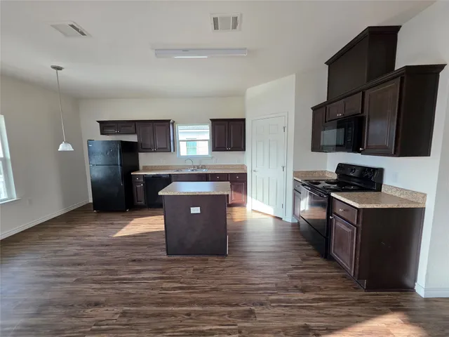 a kitchen with stainless steel appliances wooden floor and a refrigerator