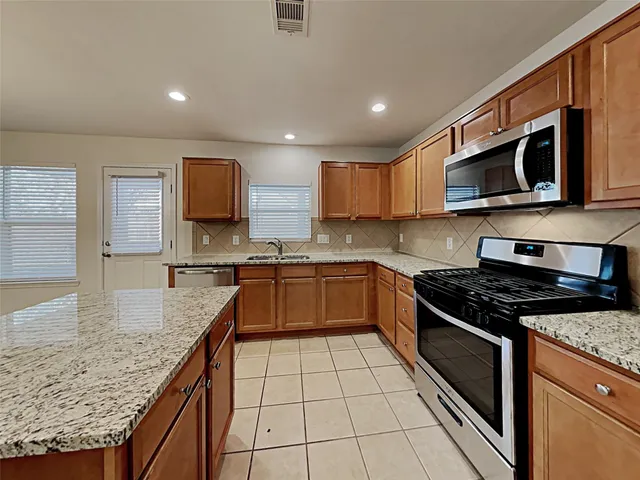 a kitchen with stainless steel appliances granite countertop a stove a sink and a microwave