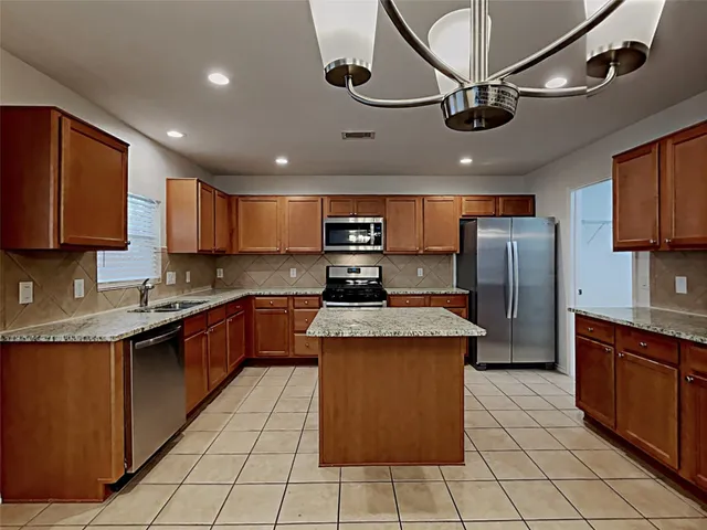a kitchen with stainless steel appliances granite countertop a stove a sink dishwasher and a refrigerator