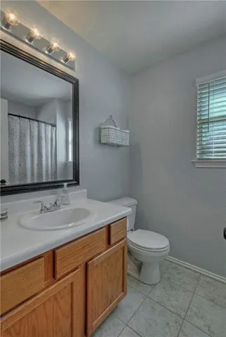 a bathroom with a granite countertop toilet sink and mirror
