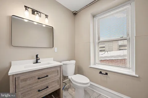 a bathroom with a toilet a sink a vanity and mirror