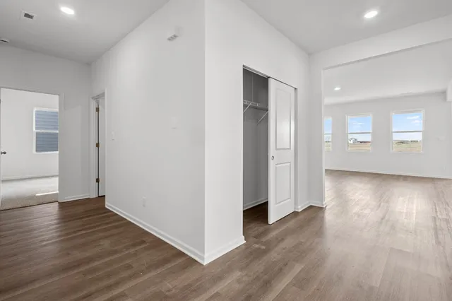 an empty room with wooden floor & windows and bathroom
