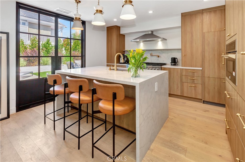 418 East 16th Street Costa Mesa, CA 92627 - Photo 11 of 28 a kitchen with stainless steel appliances granite countertop a stove a refrigerator a sink a dining table and chairs with wooden floor