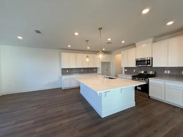 a large kitchen with stainless steel appliances granite countertop a white stove top oven and white cabinets
