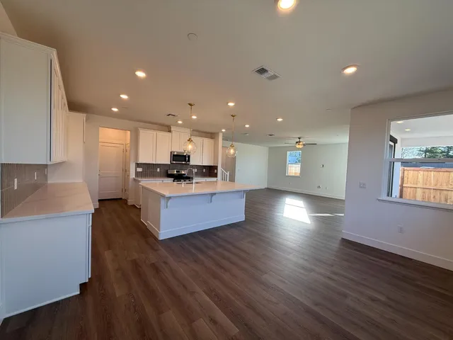 a large kitchen with stainless steel appliances granite countertop a large counter top a stove and a wooden floors