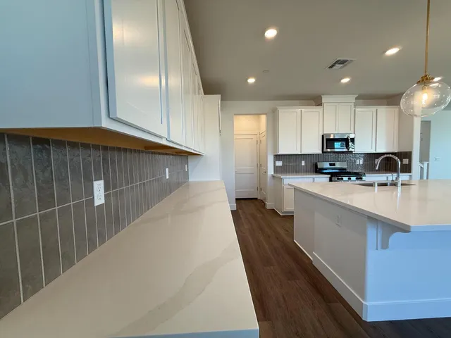a kitchen with kitchen island granite countertop a sink a counter top space stainless steel appliances and cabinets