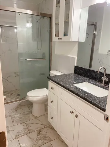 a bathroom with a granite countertop sink toilet and shower