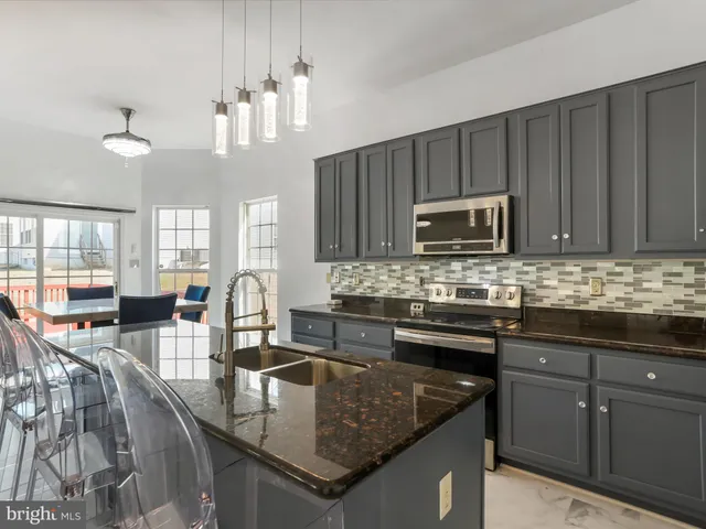 a kitchen with granite countertop a sink a stove a microwave and cabinets