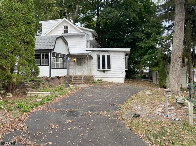 a view of a white house next to a yard with big trees