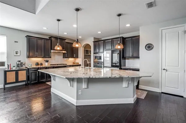 a kitchen with stainless steel appliances kitchen island granite countertop a stove a sink and a refrigerator