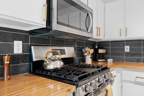 a kitchen with stainless steel appliances granite countertop a stove a sink and a microwave