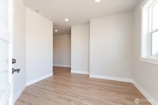 a view of an empty room with wooden floor and a window