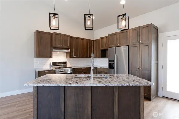 a kitchen with kitchen island granite countertop a sink a center island stainless steel appliances and cabinets
