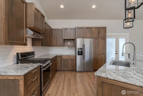 a kitchen with stainless steel appliances granite countertop a sink stove and refrigerator