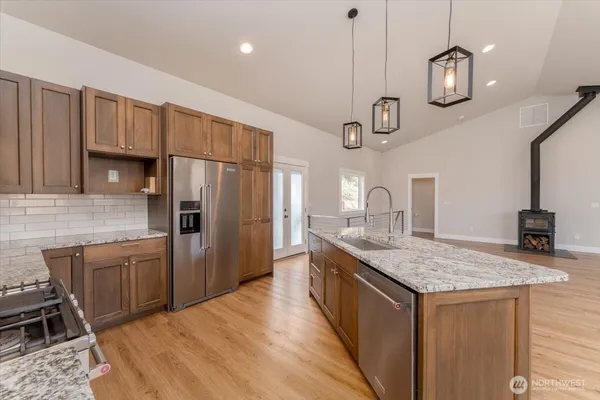 a kitchen with stainless steel appliances granite countertop a sink a stove a refrigerator cabinets and chairs