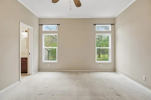 an empty room with chandelier fan and windows
