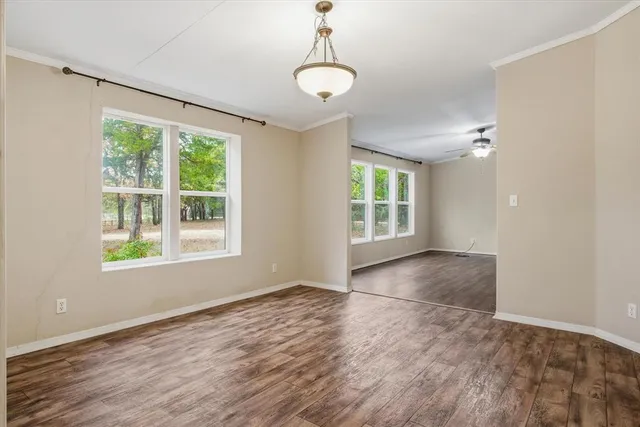 an empty room with wooden floor cabinet and windows