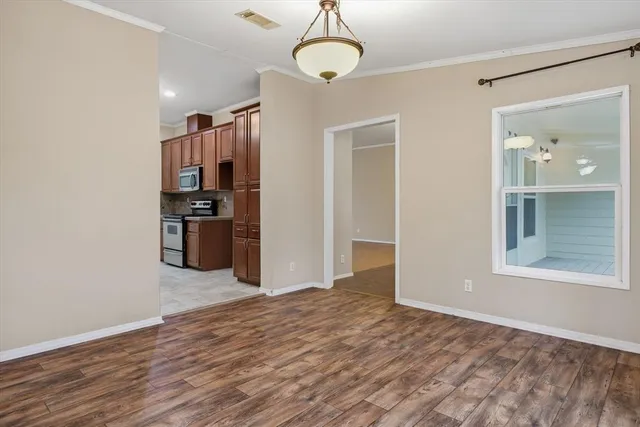 an empty room with wooden floor chandelier and windows