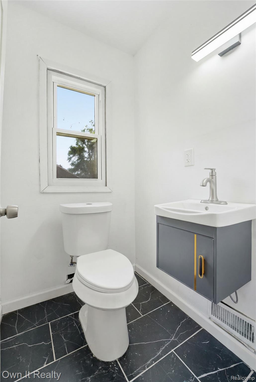 17351 Appoline Street Detroit, MI 48235 - Photo 8 of 34 Bathroom featuring dark tiled flooring, a window, a white toilet, and a wall-mounted vanity with a single basin sink