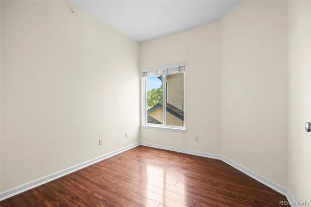 an empty room with wooden floor and window