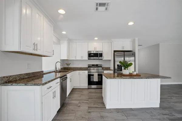 a kitchen with kitchen island granite countertop counter top space appliances and cabinets