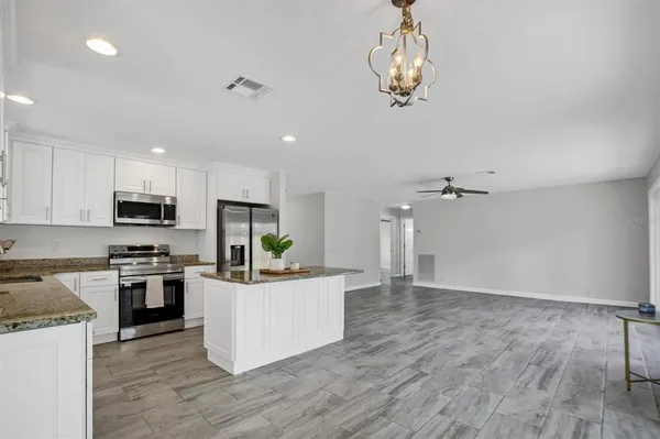 a kitchen with granite countertop a stove top oven a sink dishwasher and a refrigerator with wooden floor