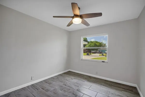 an empty room with a window and a ceiling fan