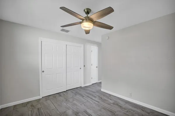 an empty room with ceiling fan and window