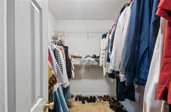 a view of walk in closet with clothes and shoes