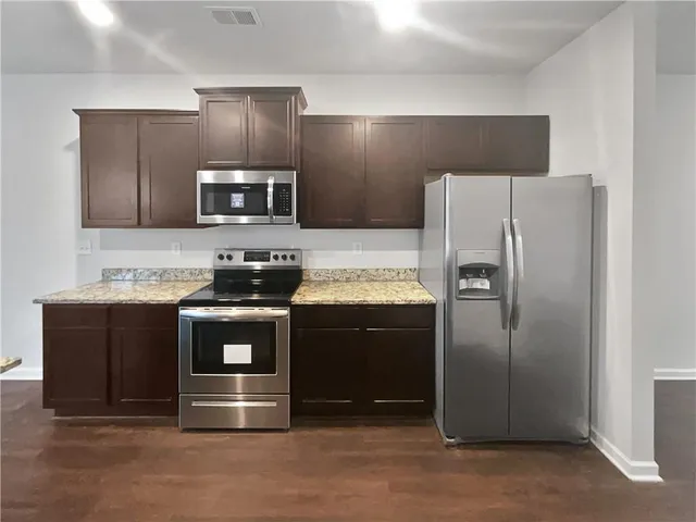 a kitchen with stainless steel appliances granite countertop a refrigerator and a stove top oven