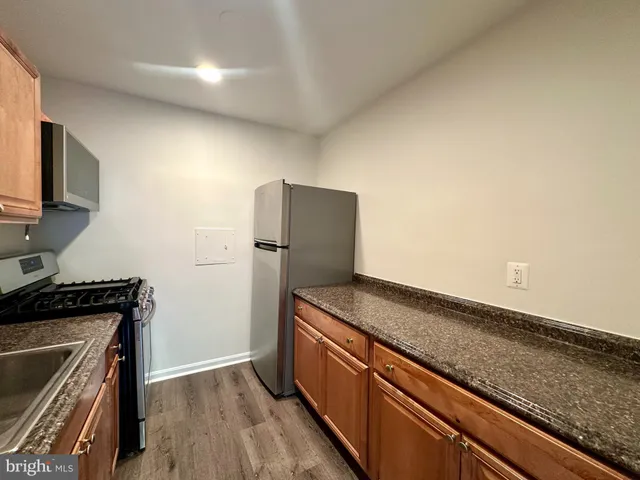 a kitchen with granite countertop a refrigerator and a stove top oven