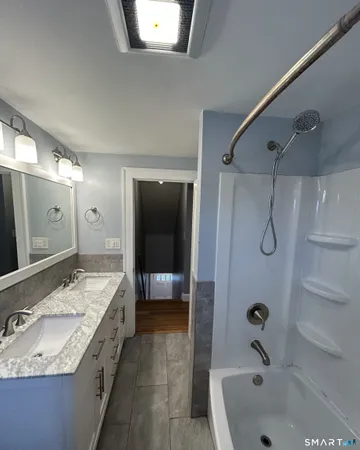 a bathroom with a granite countertop bathtub shower sink and mirror
