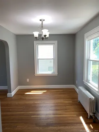 an empty room with wooden floor chandelier and glass door