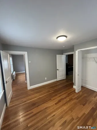 an empty room with wooden floor and mirror