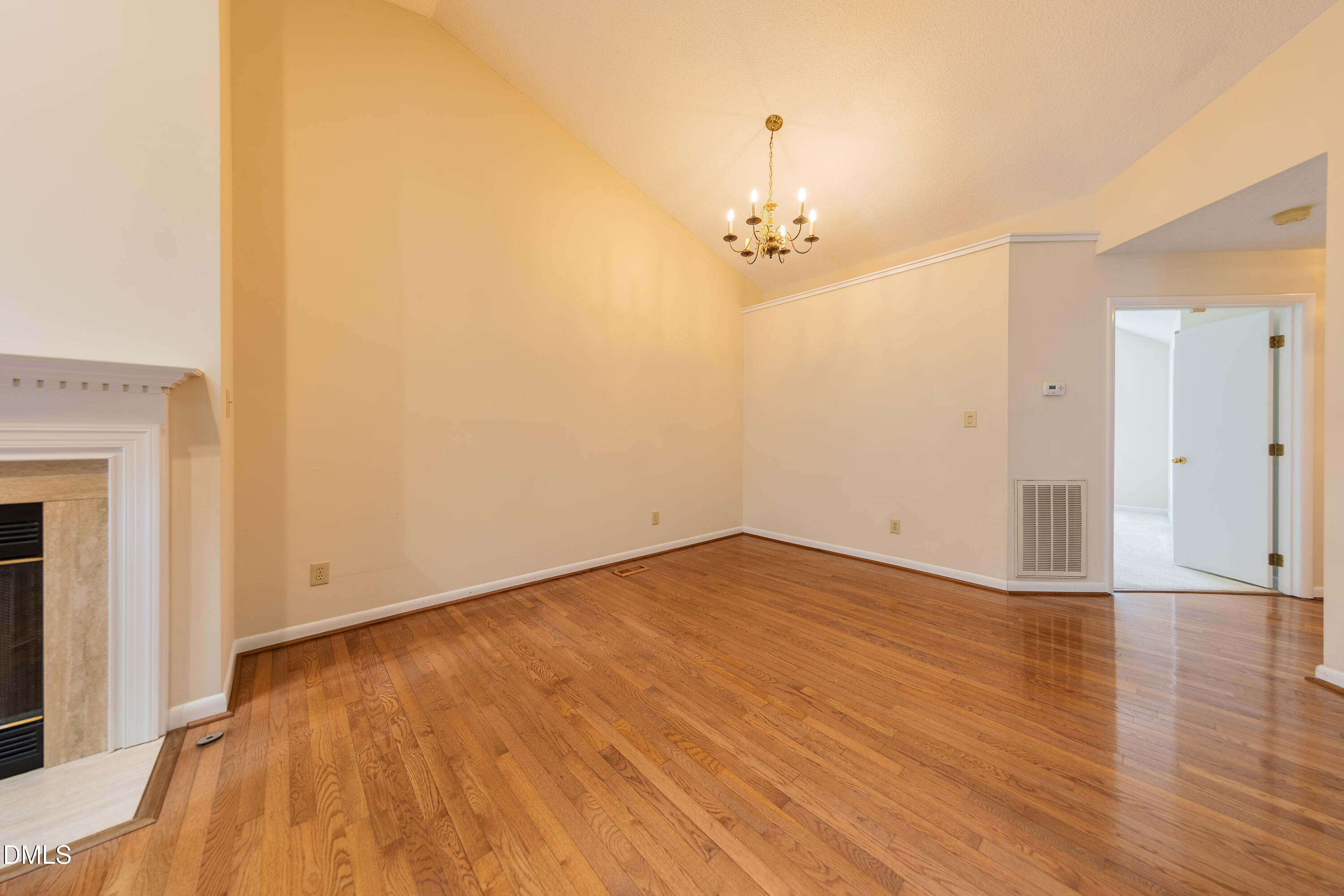 7918 Wood Cove Court Raleigh, NC 27615 - Photo 8 of 31 an empty room with wooden floor and chandelier fan