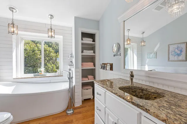 a bathroom with a granite countertop tub sink and mirror