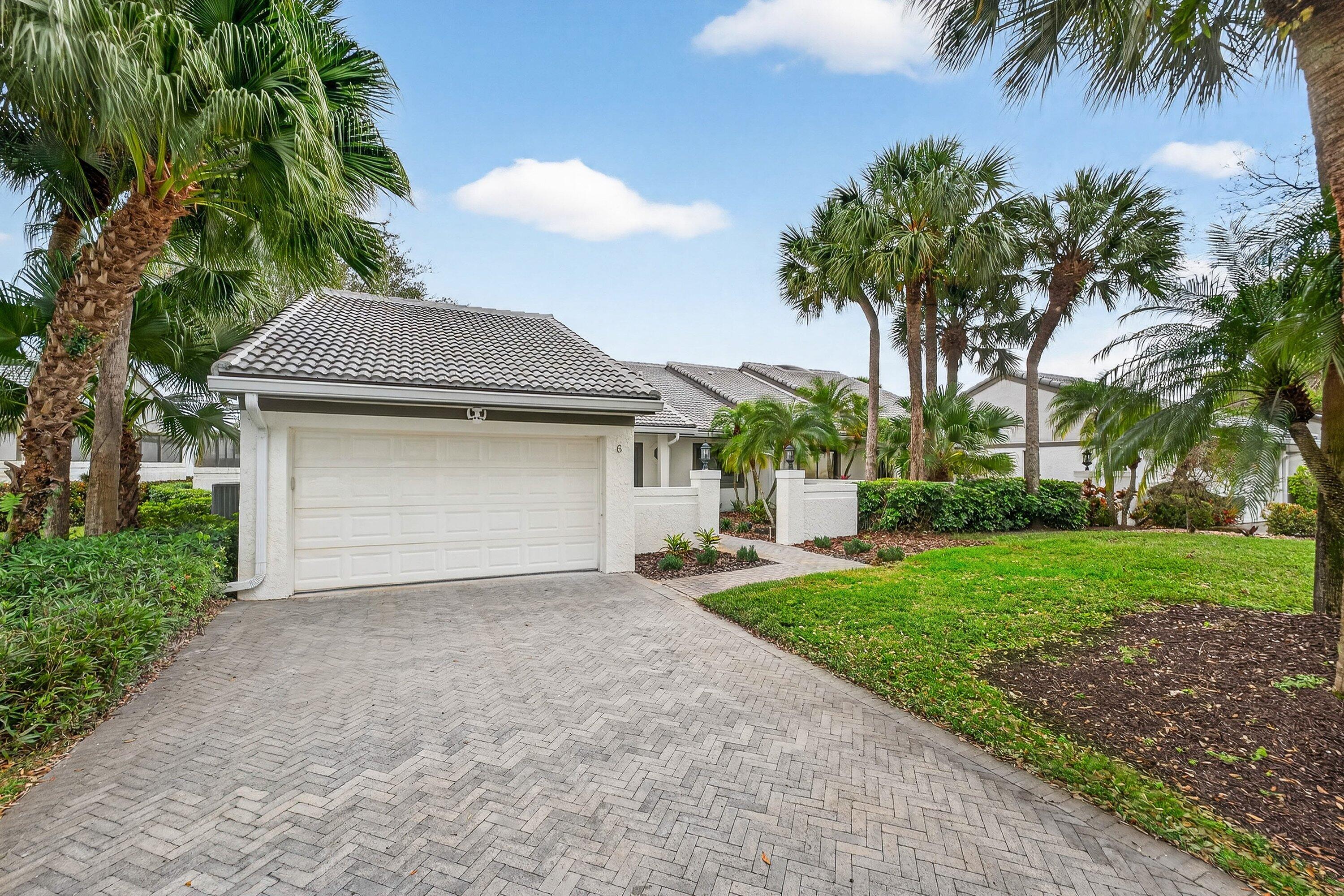 6 Clubhouse Lane Boynton Beach, FL 33436 - Photo 13 of 76 a front view of a house with a garden and trees