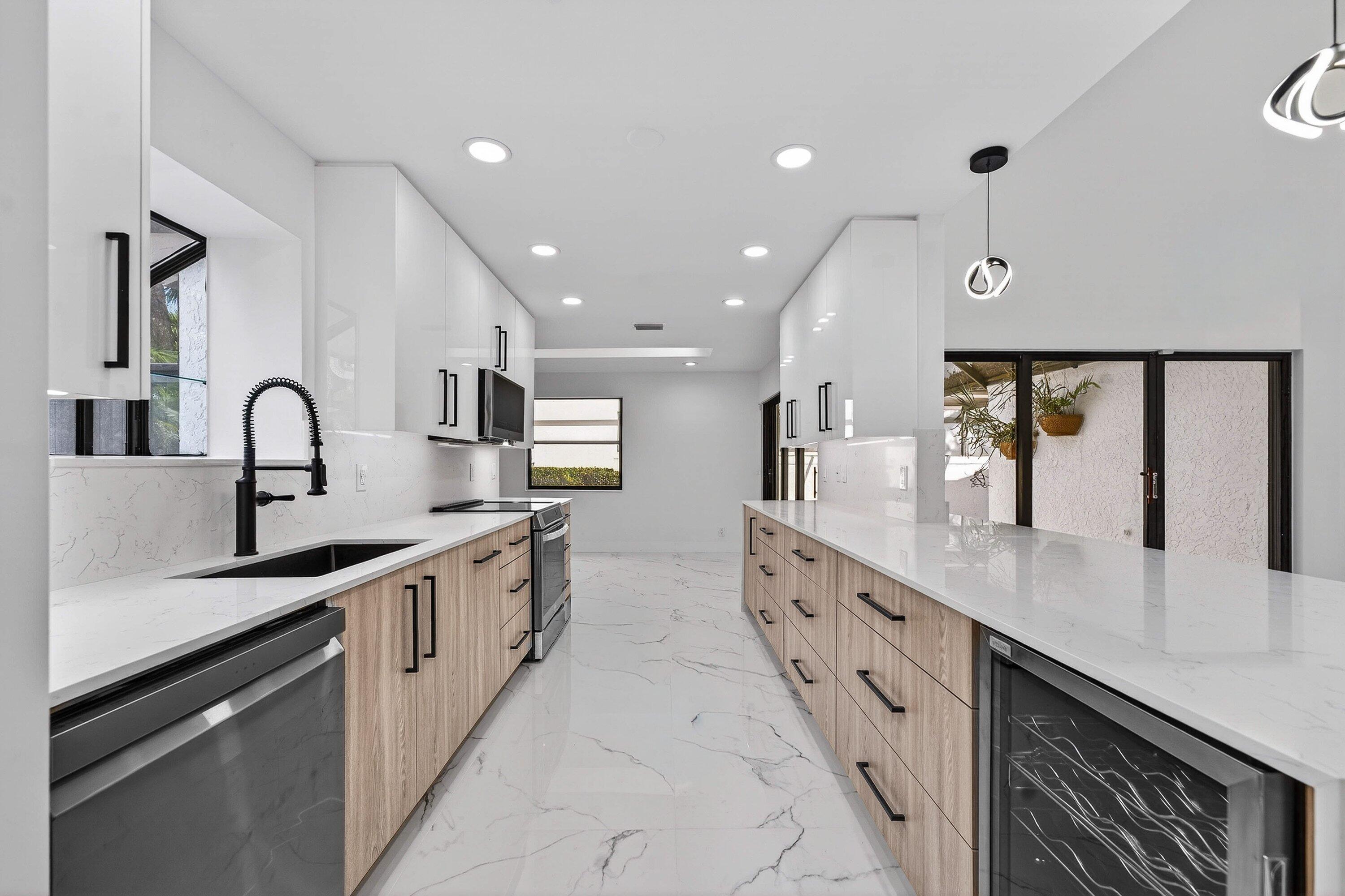 6 Clubhouse Lane Boynton Beach, FL 33436 - Photo 27 of 76 a large kitchen with stainless steel appliances a sink dishwasher a stove and a dining table with wooden floor