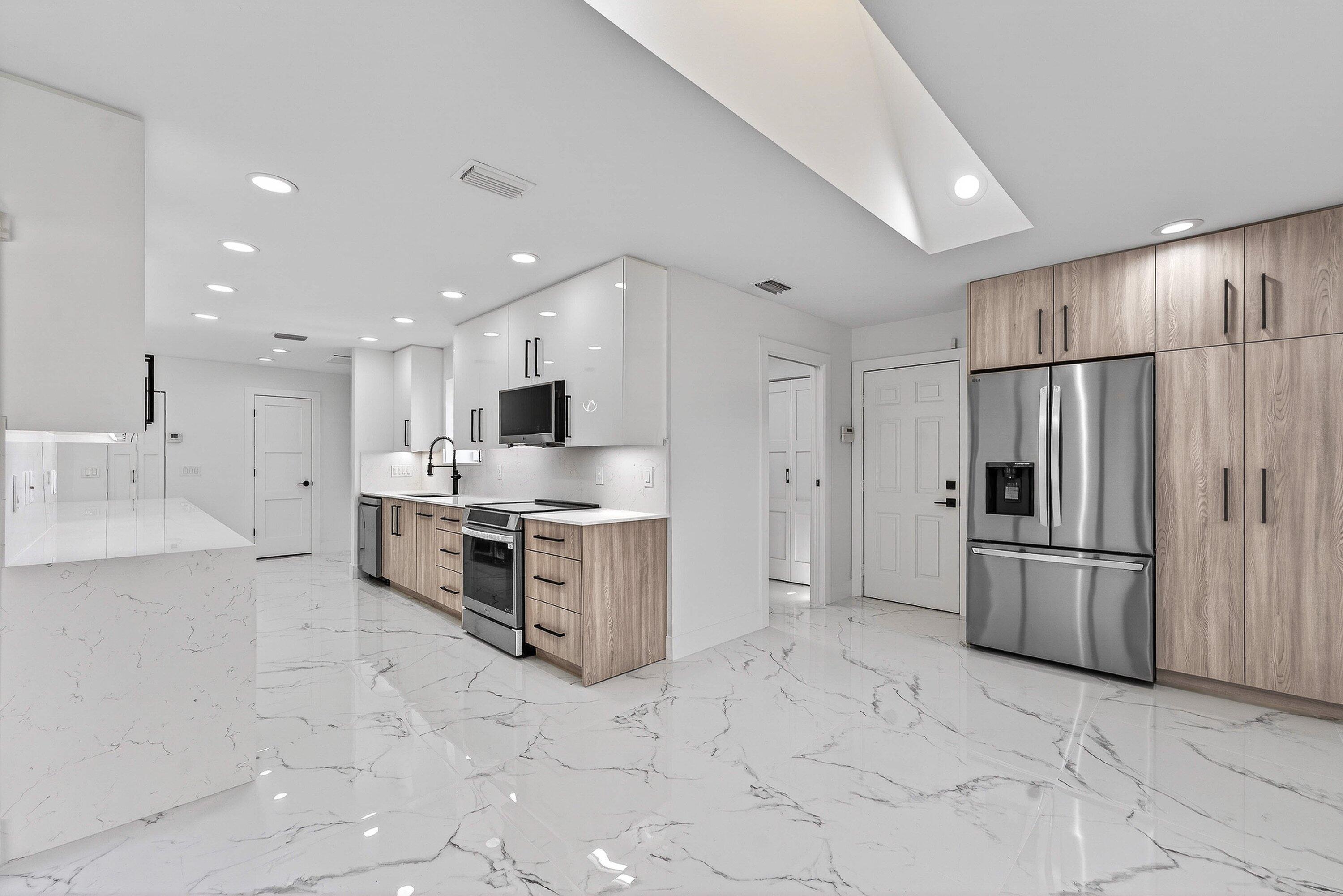 6 Clubhouse Lane Boynton Beach, FL 33436 - Photo 30 of 76 a large kitchen with stainless steel appliances kitchen island granite countertop a refrigerator and a stove top oven