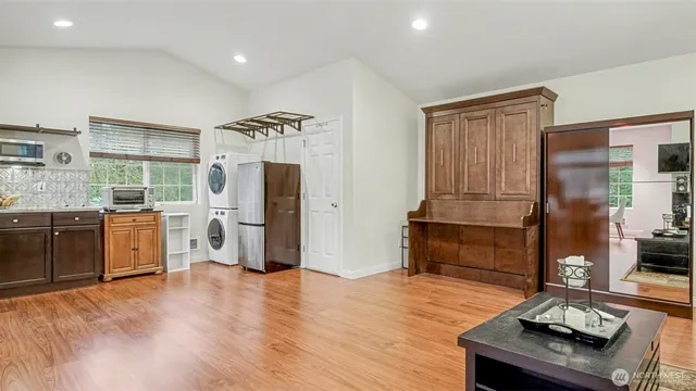 a kitchen with stainless steel appliances kitchen island granite countertop a refrigerator a sink a stove and white cabinets with wooden floor