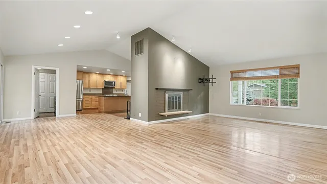 an empty room with wooden floor and a kitchen