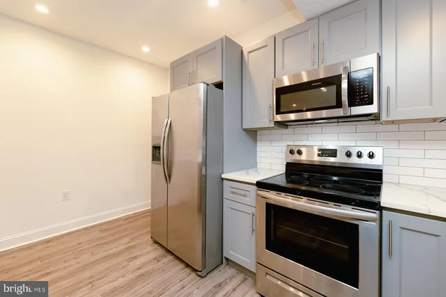 a large kitchen with stainless steel appliances a large counter top a stove and a refrigerator