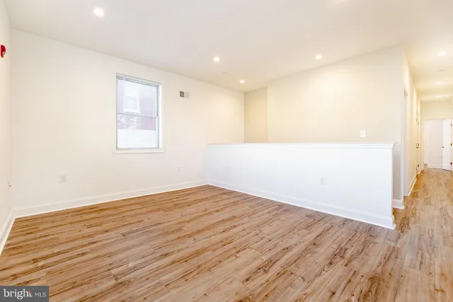 a view of an empty room with wooden floor and stairs