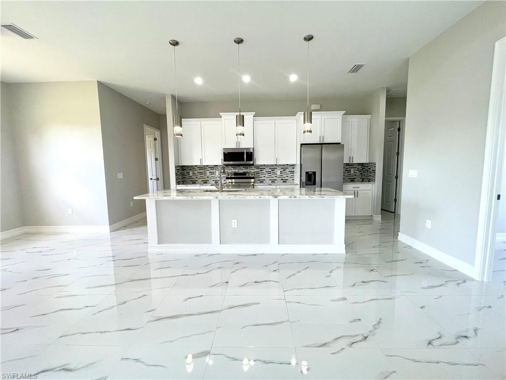 a large white kitchen with kitchen island a sink a stove and cabinets