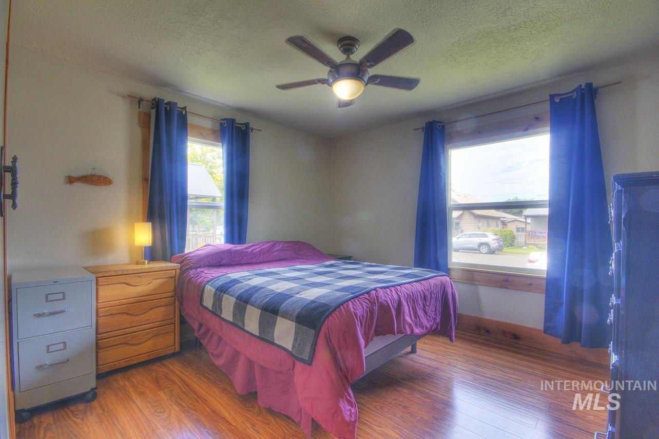 351 West Main Street South Vale, OR 97918 - Photo 22 of 33 Bedroom featuring wood-finish flooring, a ceiling fan with integrated lighting, and two windows with wood trim