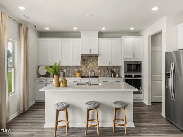 a kitchen with stainless steel appliances granite countertop a dining table chairs refrigerator and cabinets