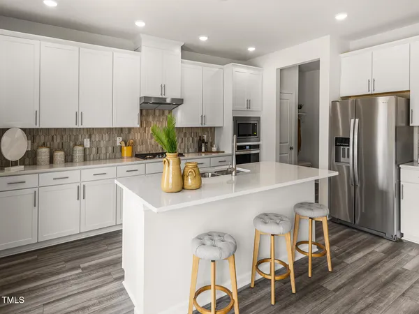a kitchen with stainless steel appliances granite countertop a refrigerator a sink a stove a dining table and chairs