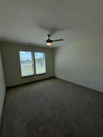 an empty room with windows and ceiling fan